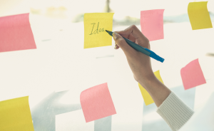 Panel de cristal donde un usuario está añadiendo un papel con ideas